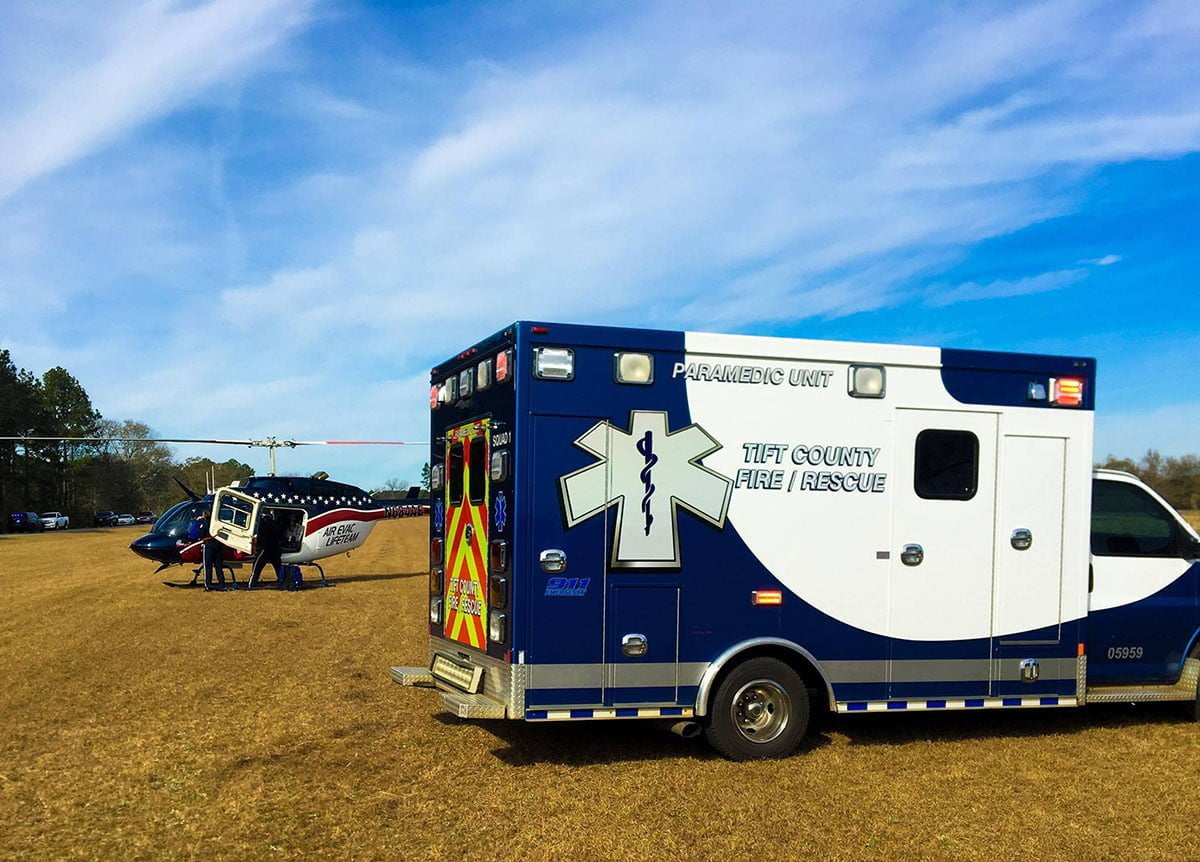 an air ambulance and a Tift County Fire/Rescue ambulance in a field.