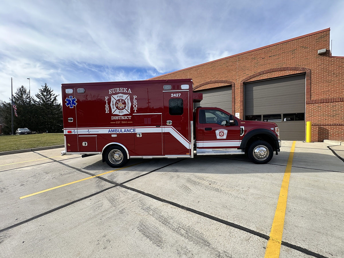 The passenger side view of the ambulance while parking in front of the fire station.